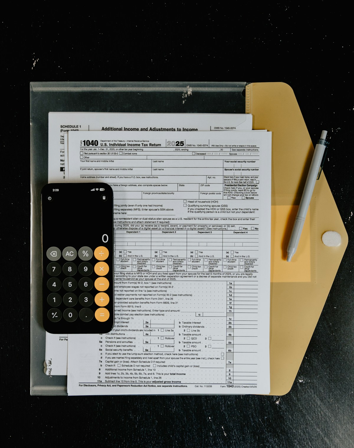 Tax forms, calculator and pen on a desk